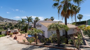 A house with a tiled roof, surrounded by palm trees and a garden.