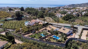 A residential area with a swimming pool, a road, and a view of the sea.