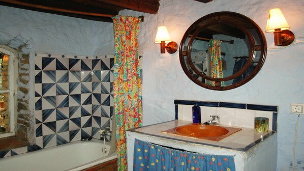 A bathroom with a bathtub, a sink, a mirror, and patterned tiles.