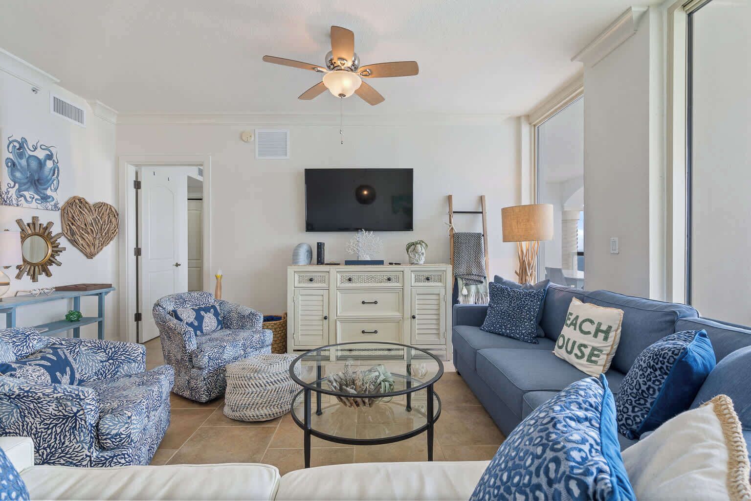 A living room with a ceiling fan, a television, a sofa, and a coffee table.