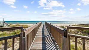 A wooden boardwalk leading to a beach with a clear sky. - Sunflower Mama, a gulf front home. (St. George Island)