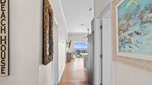 A hallway with a wooden floor, a wall-mounted sign reading "BEACH HOUSE", and a framed painting of an underwater scene. - Sunflower Mama, a gulf front home. (St. George Island)