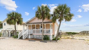 A beachfront house with a porch, palm trees, and a sandy beach. - Sunflower Mama, a gulf front home. (St. George Island)