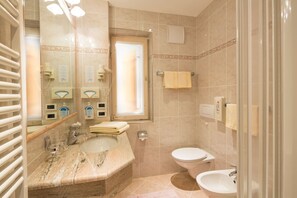 A bathroom with a marble sink, a toilet, and a glass shower enclosure.