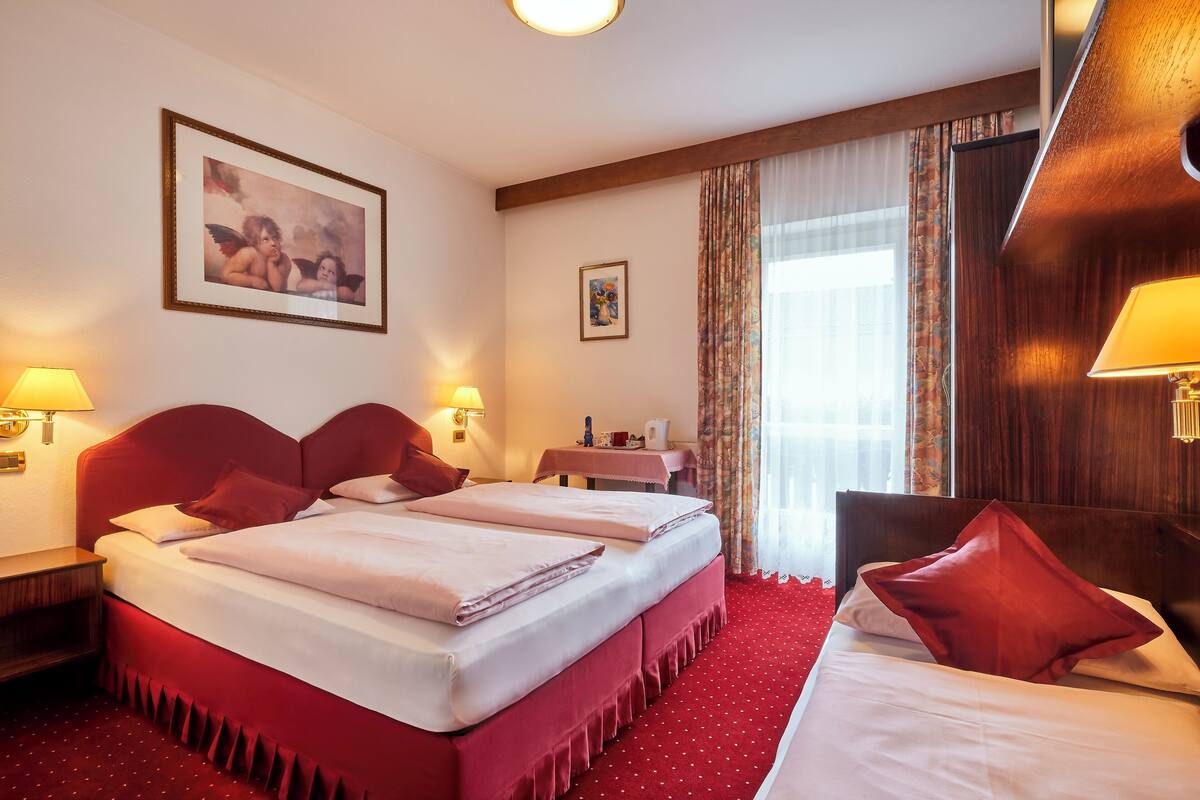 A hotel room with two beds, a desk, and a chair.