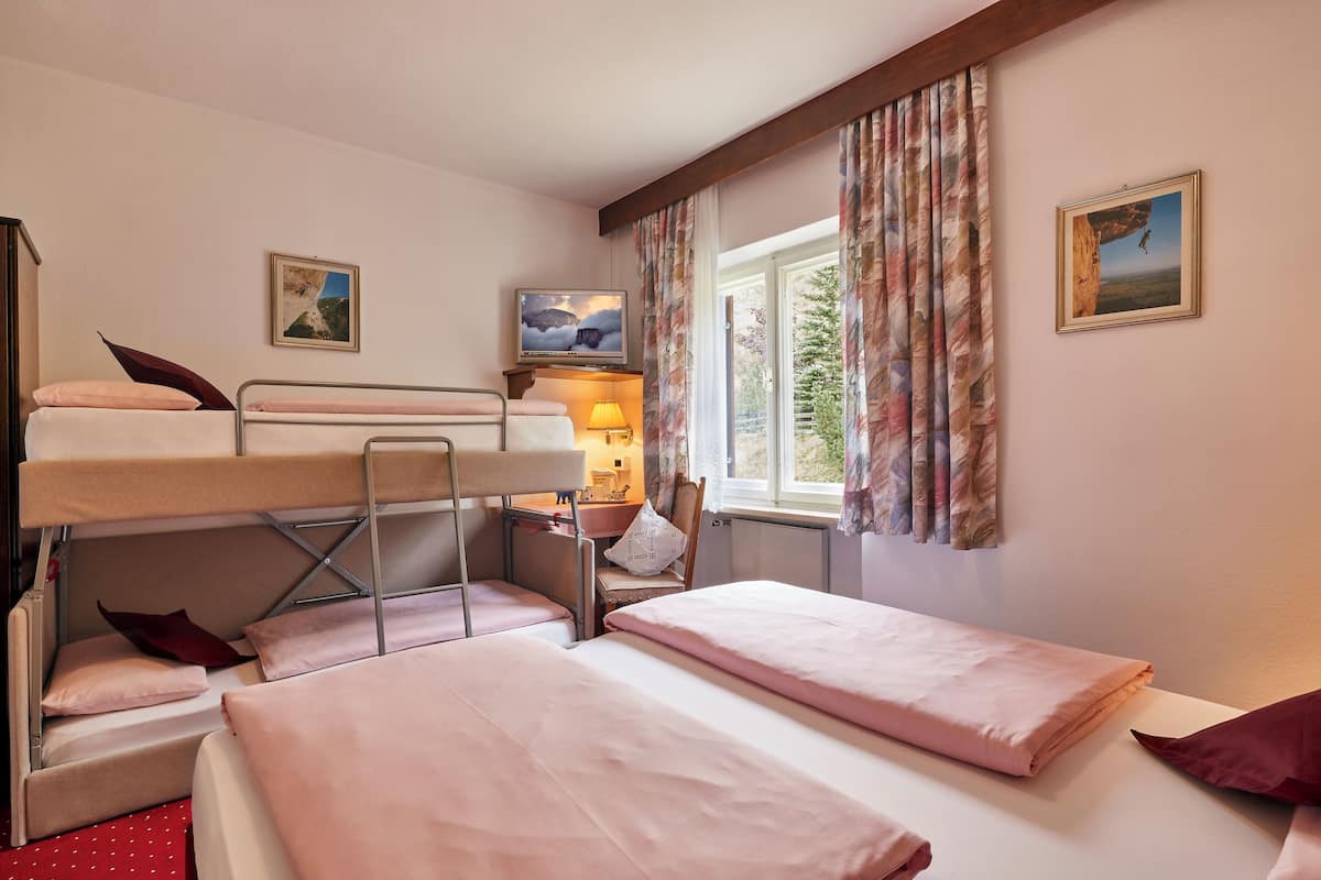 A bunk bed room with a desk, a chair, and a window with curtains.