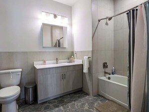 Een badkamer met toilet, wastafel, badkamermeubel en douchegedeelte.