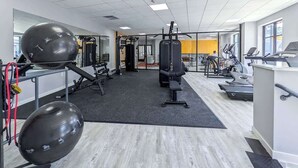 Ein Fitnessraum mit Trainingsgeräten, einer schwarzen Matte und einem Spiegel.
