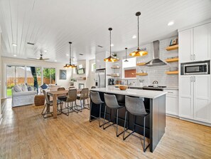 Une cuisine moderne dotée d’un grand îlot central, de tabourets de bar et d’un coin repas comprenant un canapé et des chaises.
