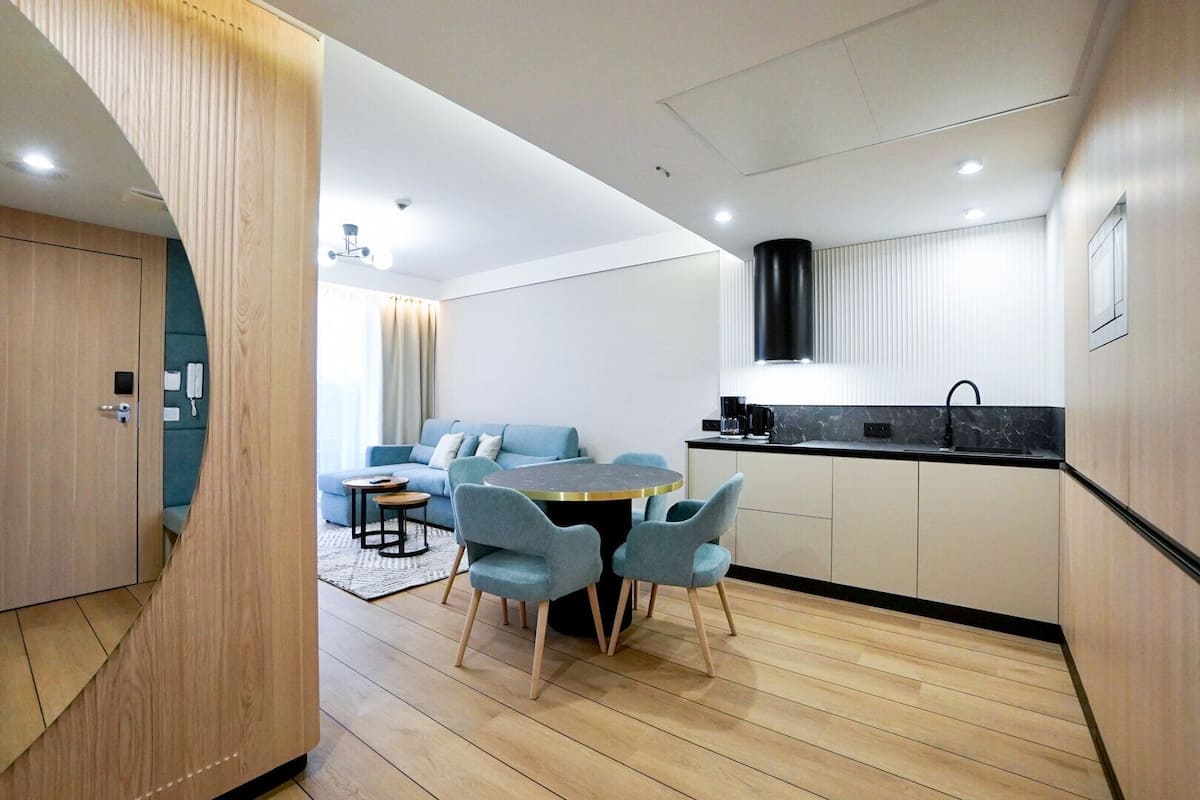 Una cocina moderna con zona de comedor, suelo de madera y un sofá azul.