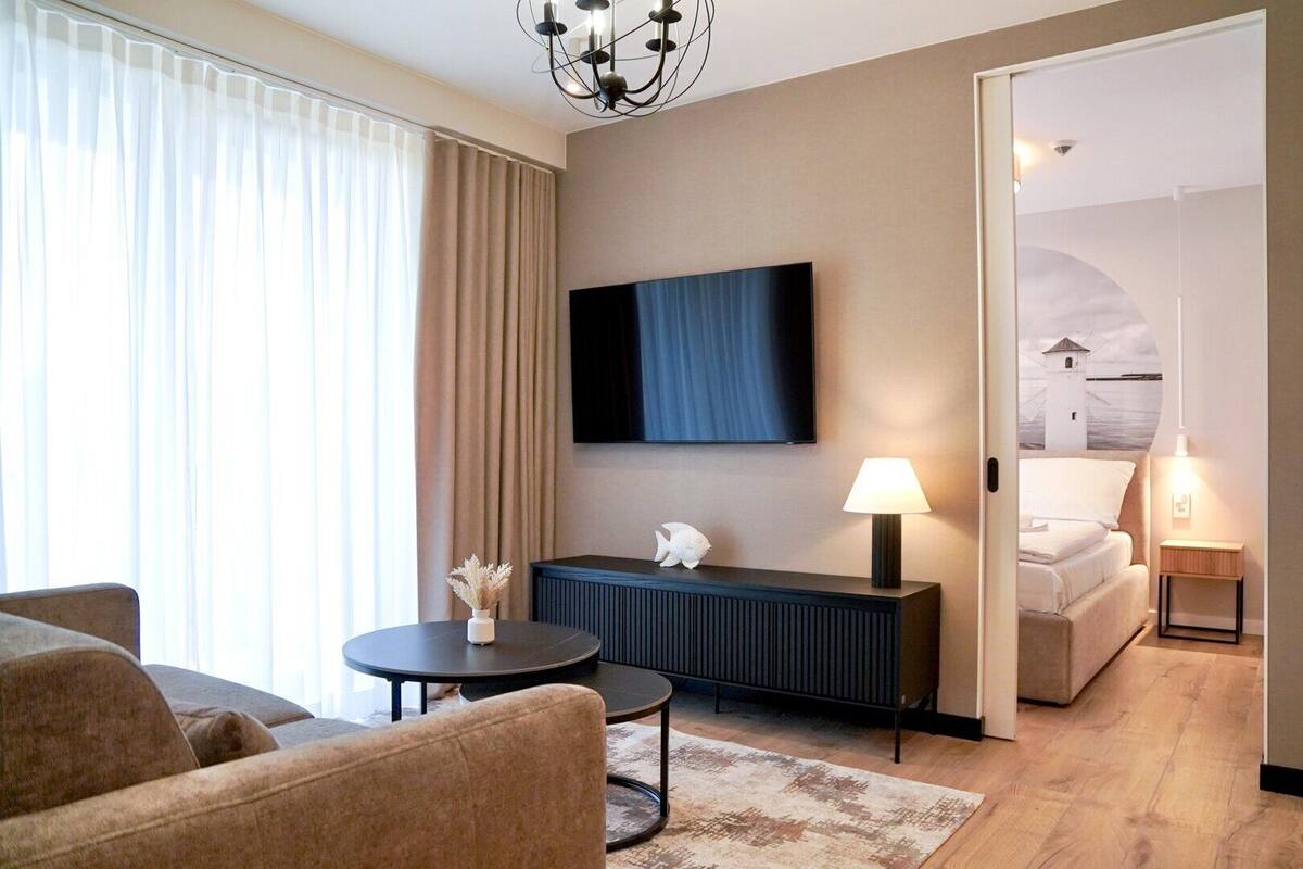 Una habitación de hotel moderna con un televisor de pantalla plana, un sofá, una mesita y una lámpara.