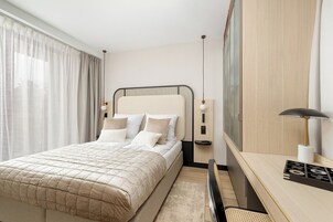 Una habitación de hotel moderna con una cama grande, un escritorio y un espejo.
