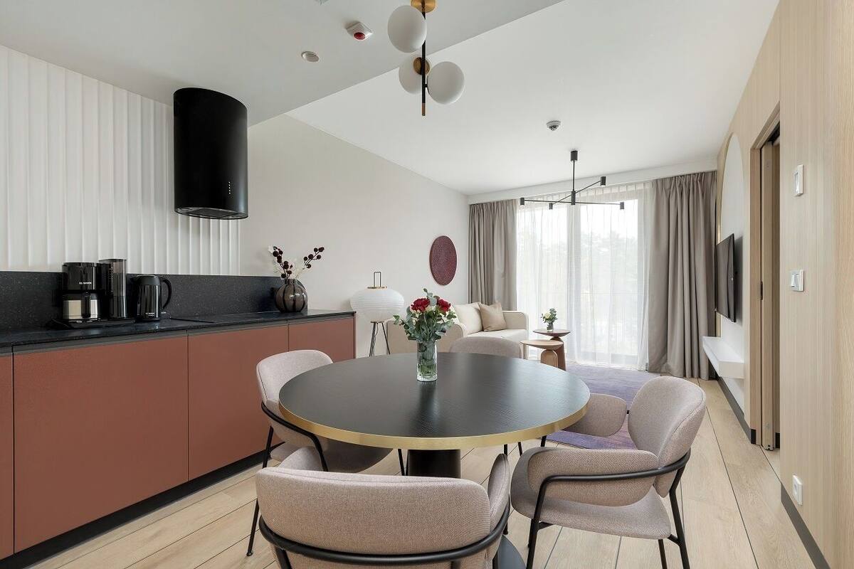 Una cocina moderna con una mesa de comedor redonda, sillas de color claro y un jarrón con flores.