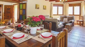 Enjoy a formal dining experience in this elegant space, complete with a long table set for a meal and a cozy living area.