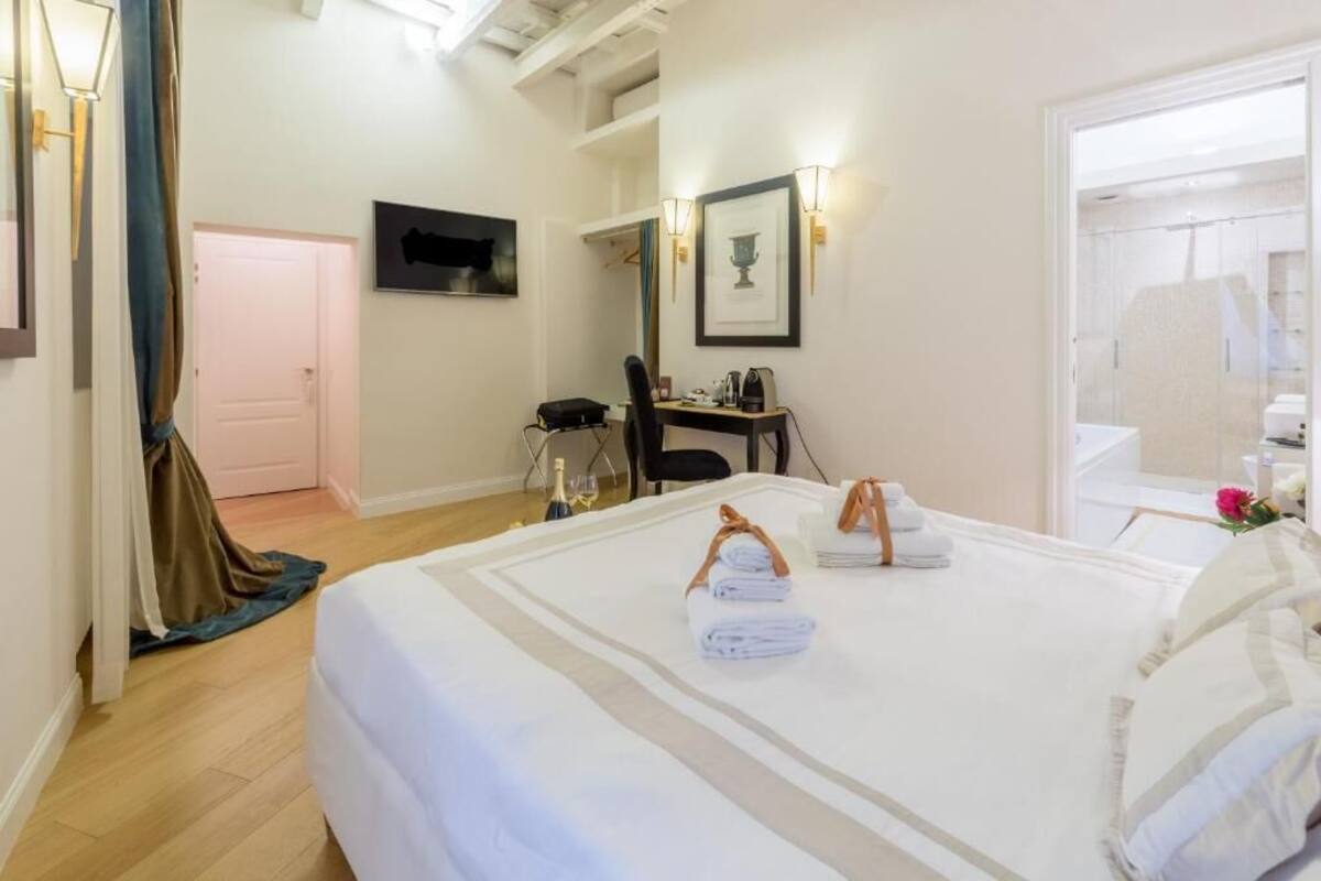 A hotel room with a bed, a desk, a chair, and a TV on the wall.