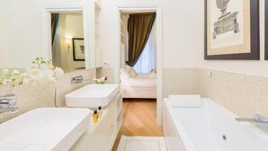 Une salle de bain moderne avec un double vasque, une baignoire et une douche. Un tableau encadré orne le mur, et un miroir est placé au-dessus de la vasque.