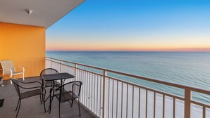 Ein Balkon mit Tisch und Stühlen mit Blick auf den Ozean.