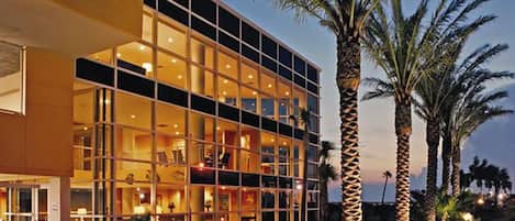 A modern hotel with a glass facade, multiple floors, and a well-lit entrance.