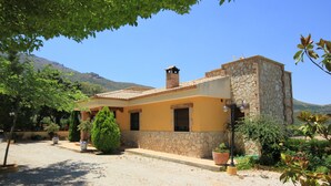 A two-story house with a stone facade, a tiled roof, and a small bell tower.