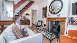 A living room with a fireplace, a staircase, a sofa, a coffee table, and a television.