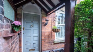 A white door with the number 10, a brick wall, a hanging plant, and a small step leading to the entrance.