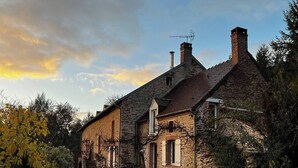 A stone house with a gravel driveway and a garden.