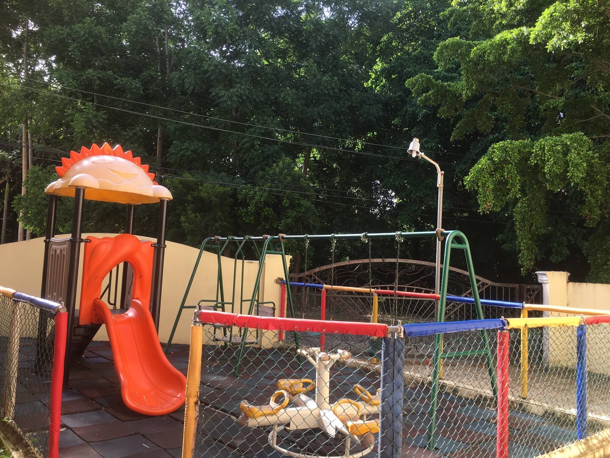 Um parquinho com escorrega, balanços e estrutura de escalada.
