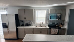Una cocina moderna con refrigerador, microondas, estufa y lavamanos.