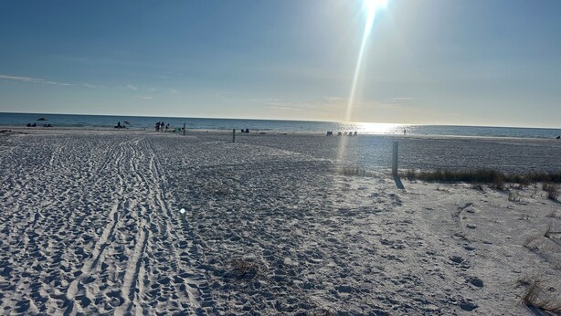 Una playa con huellas y cielo despejado.