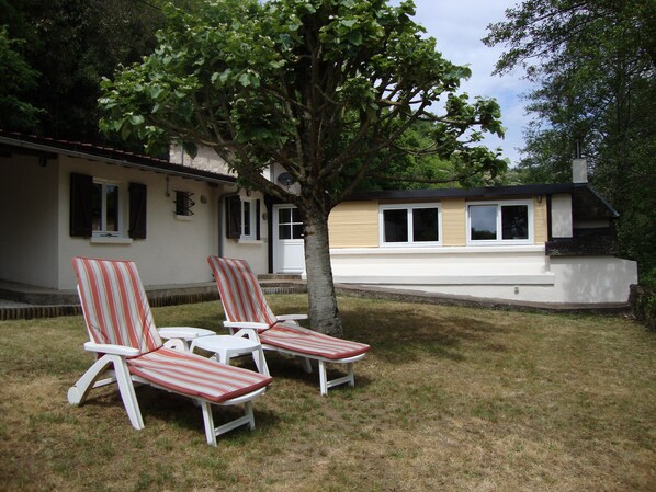 Ein Haus mit Veranda und zwei Liegestühlen.