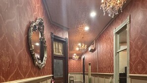 Ein Flur mit Holzboden, einem Glastisch, einer Chandelüster und einem Spiegel.