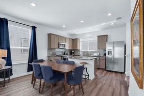 Una cocina moderna con comedor, que cuenta con armarios de madera, electrodomésticos de acero inoxidable y una isla grande.