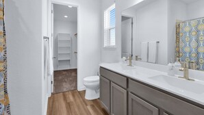 Une salle de bain moderne avec un meuble-lavabo blanc, un grand miroir et un espace douche.
