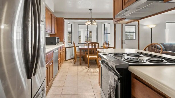 A modern kitchen with stainless steel appliances, wooden cabinets, and a dining area with chairs and a table. - 4BR Glendale Ranch - Family & Horse Friendly! (Glendale)