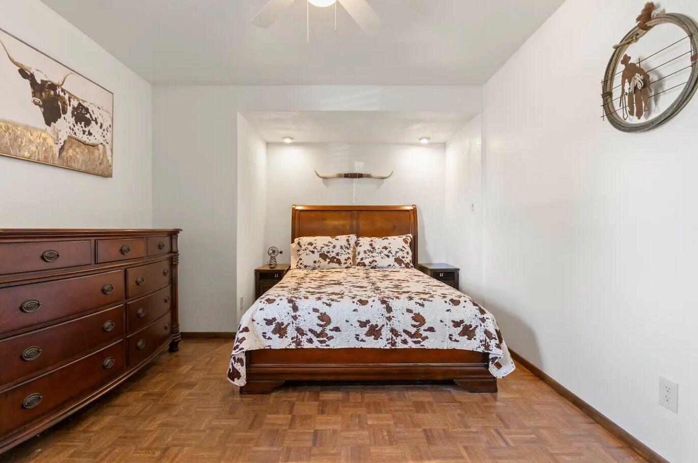 A bedroom with a wooden bed, a dresser, and a wall-mounted light fixture.
