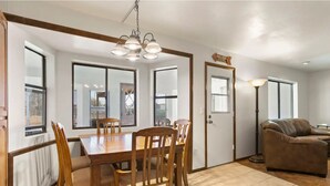 A dining area with a wooden table and chairs, a chandelier, and large windows. - 4BR Glendale Ranch - Family & Horse Friendly! (Glendale)