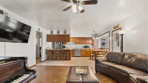 A living room with a piano, a leather sofa, and a dining area with wooden chairs. - 4BR Glendale Ranch - Family & Horse Friendly! (Glendale)