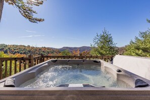 A hot tub with a wooden deck and a scenic view of autumn trees and mountains. - Hawk's Rest: Private Cabin, Great Views, Hot Tub, WIFI, Fireplace (Ferguson)