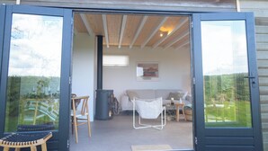 Una puerta corrediza de vidrio abierta que da a una sala de estar con un sofá, una silla y una mesa.