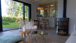 Una sala de estar acogedora con chimenea, comedor y vistas al jardín.