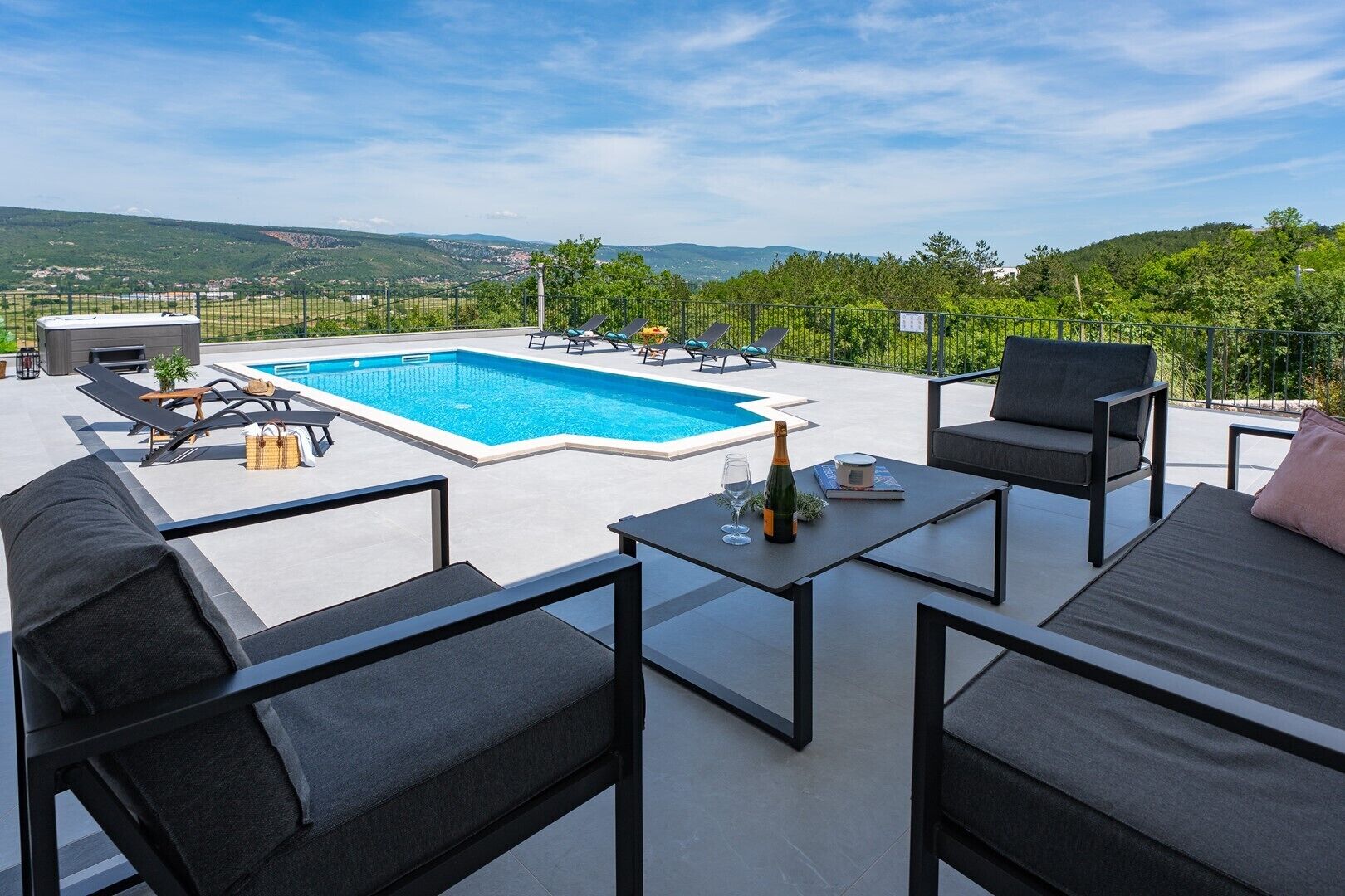 A rooftop terrace with a swimming pool, outdoor furniture, and a scenic view of the countryside.