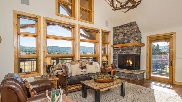 A cozy living room with a fireplace, large windows, and a leather sofa. - Enchanting Home! 10 Min Drive to Resort, 5 Min to Town Center! (Big Sky)