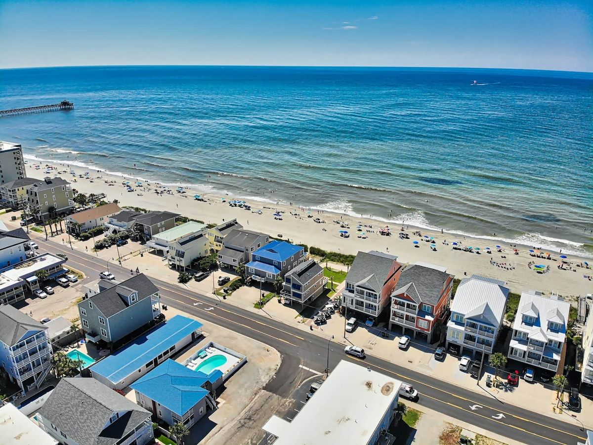 A coastal town with a beach, buildings, and a pier.