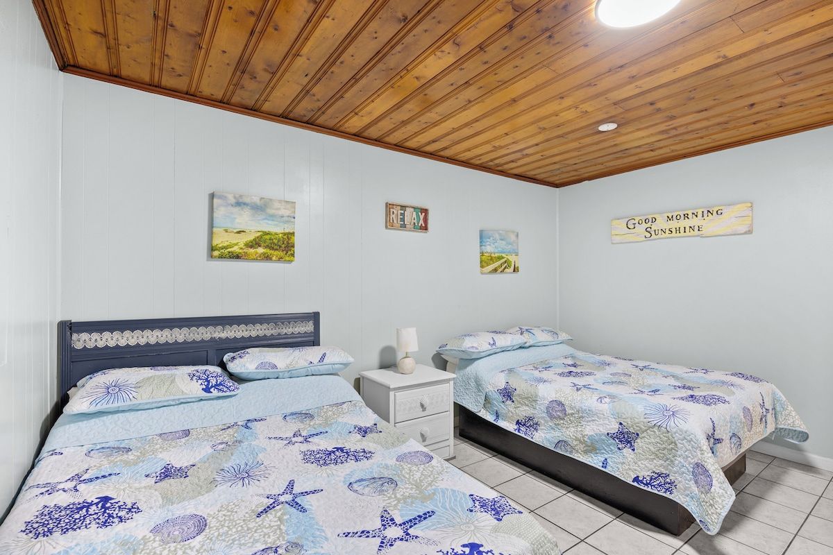 A bedroom with two beds, a nightstand, and wall decorations.