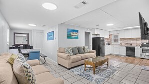 Un salon moderne avec un canapé beige, une table basse et un coin repas comprenant une table et des chaises.