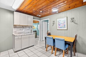 A kitchen with white cabinets, a wooden dining table, and blue chairs.