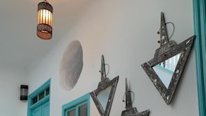 A room with a teal door, a window, a table with a red cloth, and wall-mounted mirrors. - Riad Darko  (Essaouira)