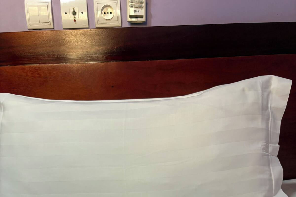 A hotel bed with a white pillow and a logo on the headboard.