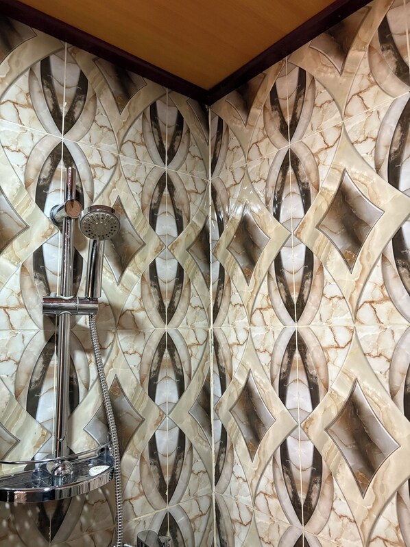 A bathroom with a shower head mounted on a wall with a marble pattern. - HOTEL LE KREMLIN (Yaoundé)