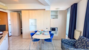 A compact living space with a dining area, kitchenette, and a sofa. - Il Giardino Delle Farfalle by Ca-sa Check (Chioggia)